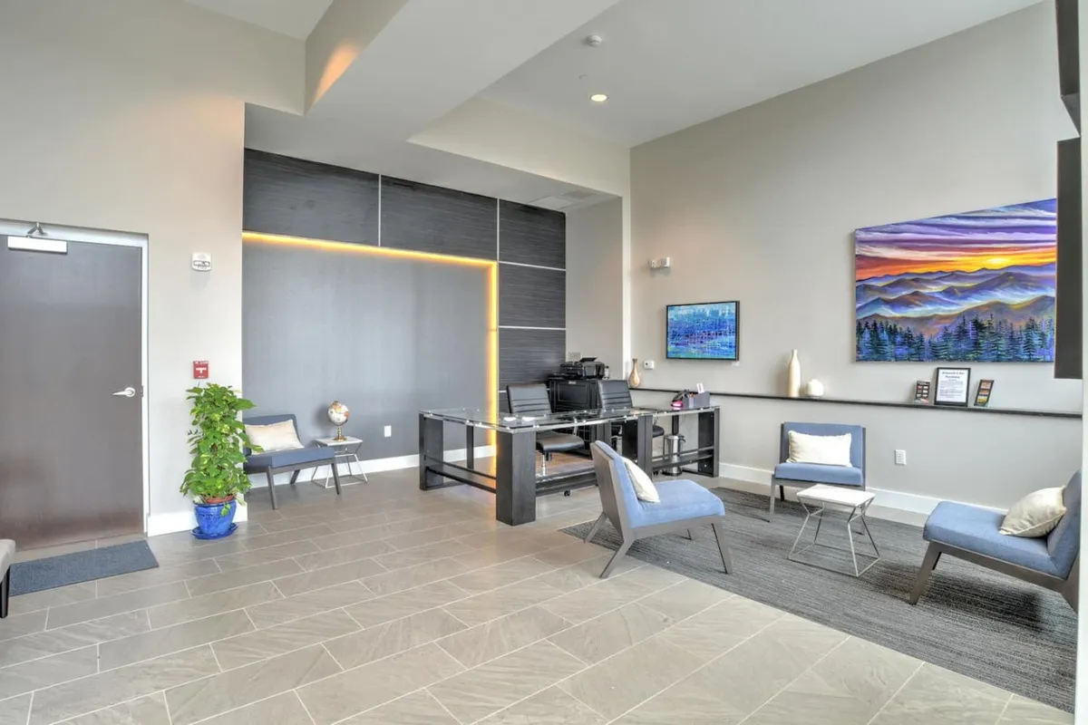 This interior shot shows a professional, inviting lobby or office space with a desk equipped with a computer, modern artwork, and a comfortable seating area. The overall atmosphere is welcoming yet efficient, hinting at attentive support and guest services.