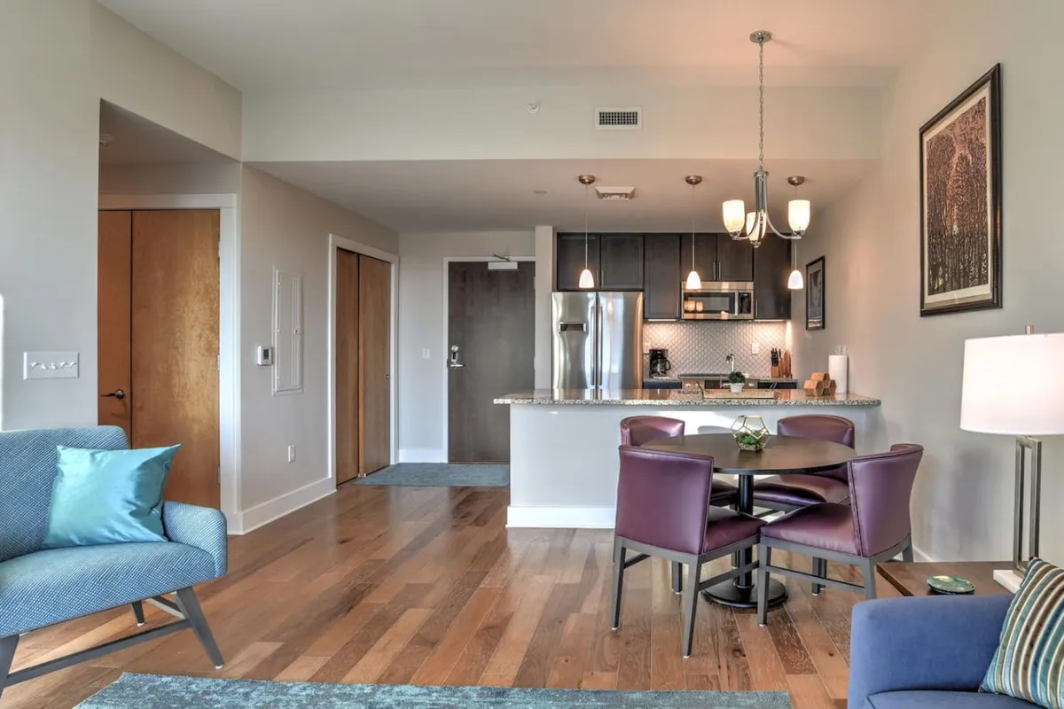 A contemporary kitchen area flows seamlessly into a dining space and a cozy seating zone. The arrangement suggests an inviting atmosphere for shared meals, casual conversations, and relaxed evenings, with soft lighting enhancing the comfortable ambiance.