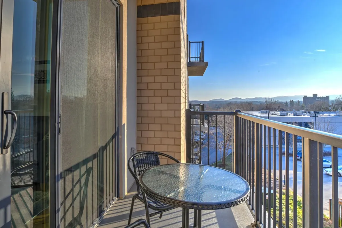 A tranquil exterior shot of the balcony’s dining table set against a backdrop of the Blue Ridge Mountains, ideal for relaxing with morning coffee or watching the sky change at sunset.